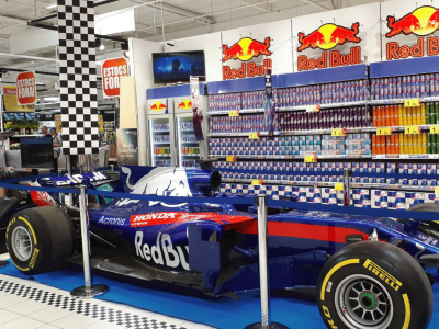 La imagen muestra un formula 1 con diseño Red Bull dentro de una tienda.