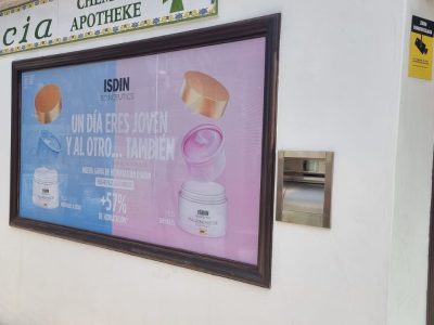 La imagen muestra un vinilo de Isidin en una tienda preparado por Merchanservis.